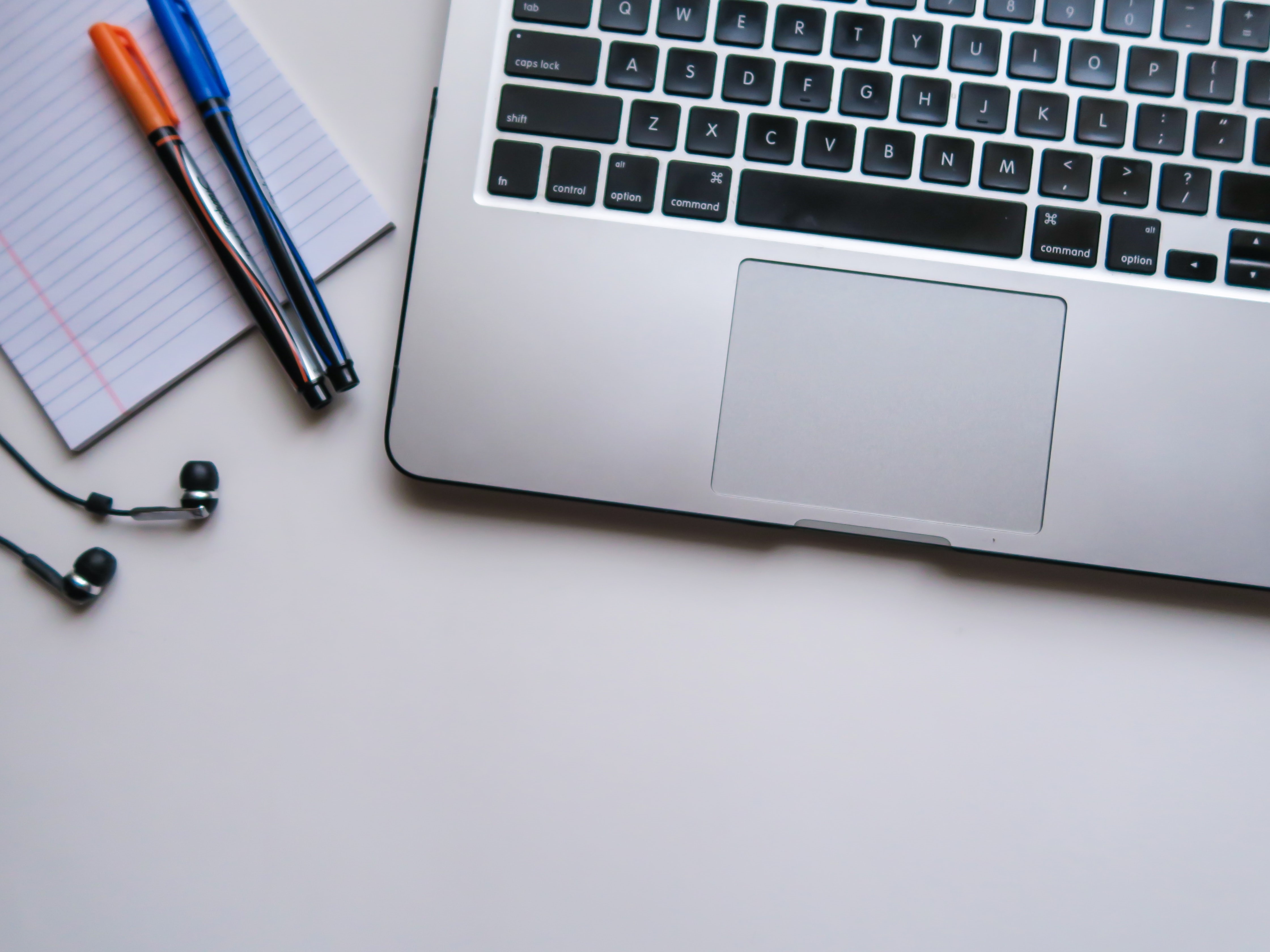 notepad and pens next to a laptop